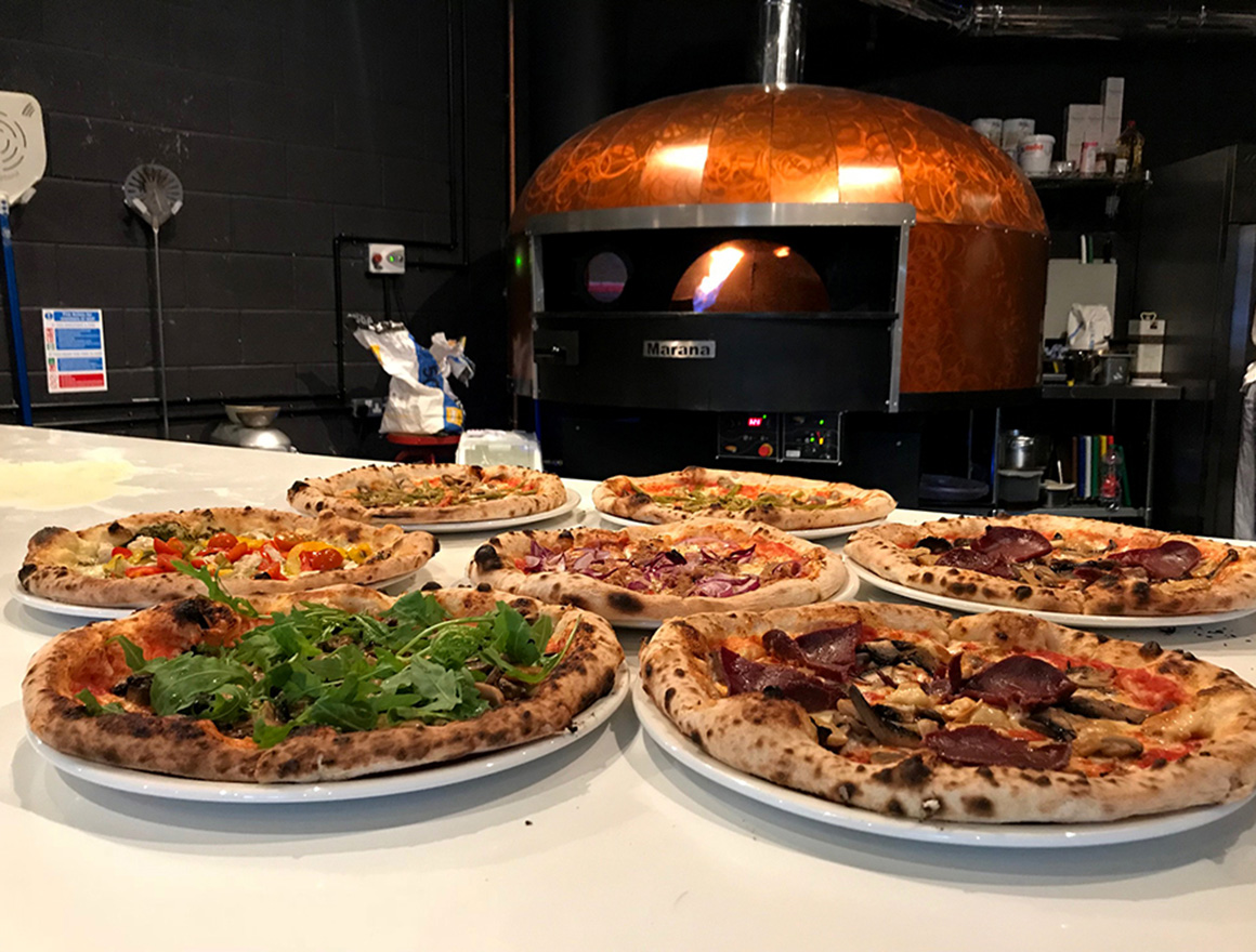 Served Pizzas with Pizza Oven in the background